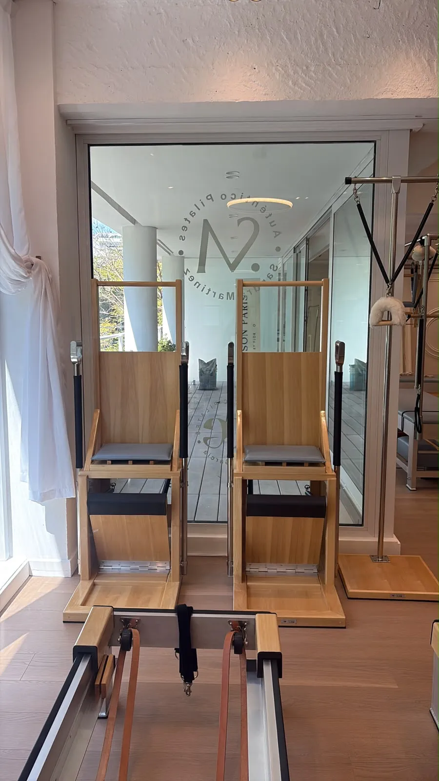 Dos Wunda Chair frente al vidrio con el sello de Auténtico Pilates Sandra Martínez